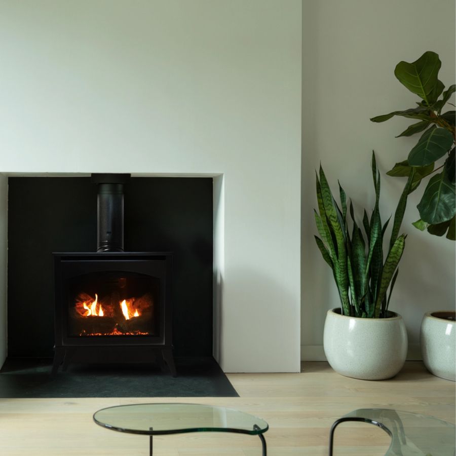 Black wood-burning fireplace with visible flames featuring an Empire Spirit 27-Inch Propane Gas Direct Vent Medium Steel Stove.